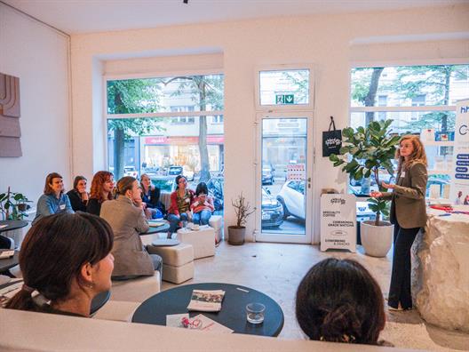 Das Bild zeigt die Veranstaltung Female Founders, bei der eine Gründerin in einem Café ihre Gründungsgeschichte mit anderen Frauen teilt.